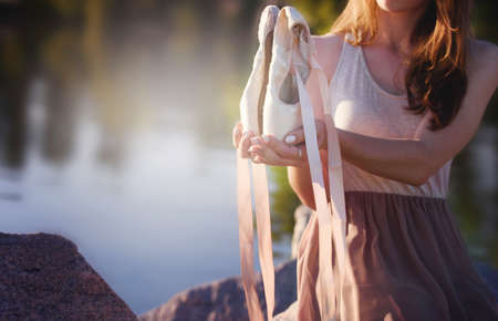 Young beautiful girl, by the sea, holds pointe shoes in her hands. Ballerinaの写真素材
