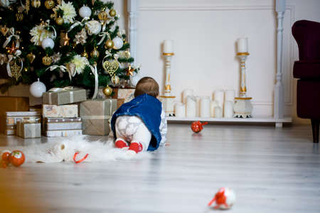 A small child crawls to new-year gifts and toys. New Year. Holidays content.