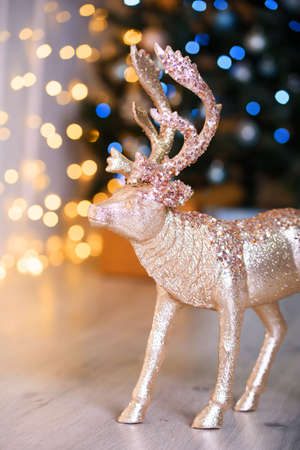 Beautiful decor in the style of the day, bright large bokeh in the background. Golden deer on the floor. Holidays.の写真素材