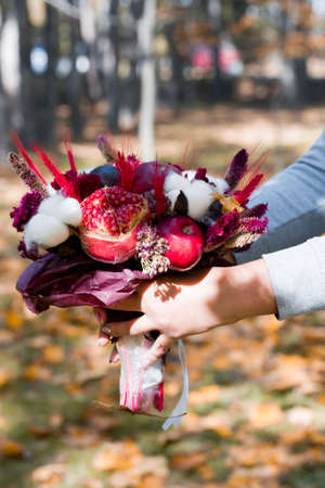 Beautiful fruit bouquet of apples, pomegranates, flowers, cotton. Fruit bouquet in the autumn in the park.の写真素材
