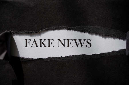 Fake news printed on a white background with black torn paper.の写真素材