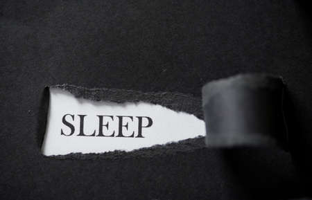 Word SLEEP printed on a white background with black torn paper. Want to sleepの写真素材