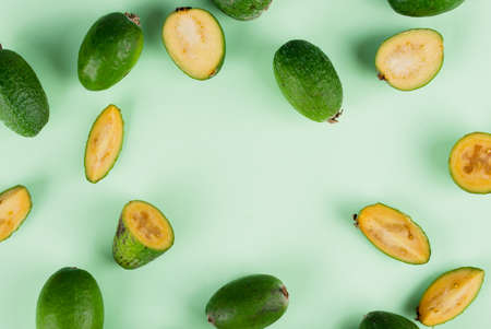 Fresh feijoa fruits with slices on a mint background. Top view.