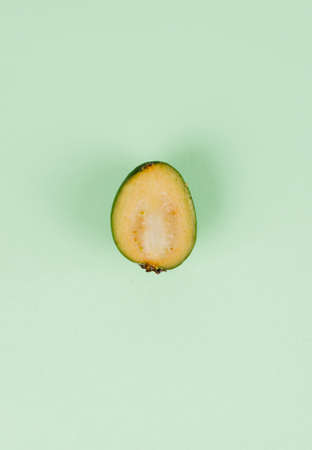 Fresh feijoa fruits with slices on a mint background. Top view.