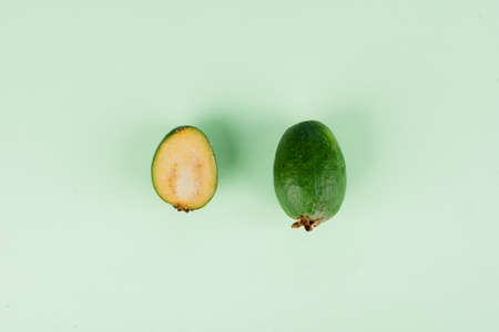 Fresh feijoa fruits with slices on a mint background. Top view.