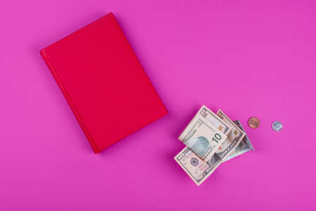 Money of various denominations and various notes with a red notebook for notes on a pink background. Business contentの写真素材