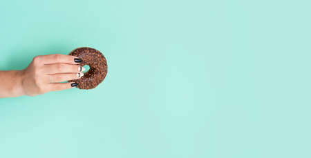 Appetizing donuts with icing on a colored background with female hands with a beautiful manicure. Trend photoの写真素材