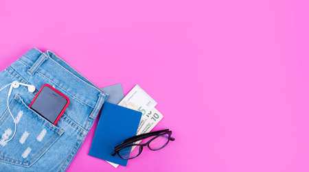 Banner on pink background with blue jeans, money, headphones, 5g internet phone, glasses. Flat lay, long bannerの写真素材