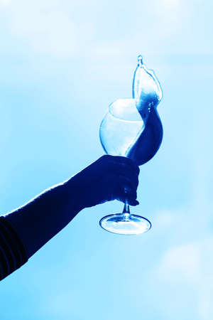 Two glasses with wine in hand against the sky . Pink drinkの写真素材