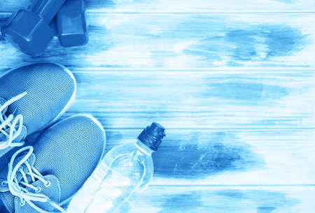 Sports games, dumbbells, drinking water on a wooden table. Blue color of the yearの写真素材