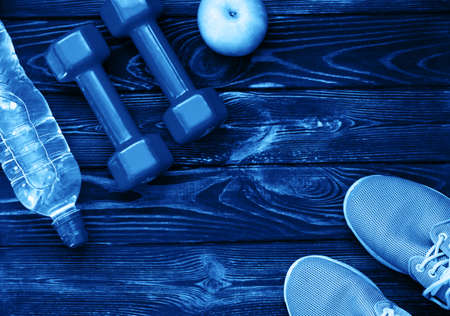 Sports games, dumbbells, drinking water on a wooden table. Blue color of the yearの写真素材