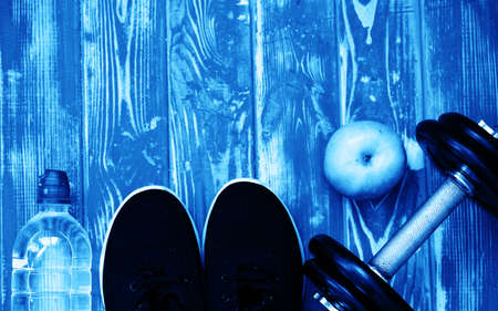 Sports games, dumbbells, drinking water on a wooden table. Blue color of the yearの写真素材