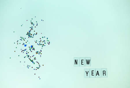 Mint background with sequins of small multi-colored stars and New Year's eve inscription. Flay layの写真素材