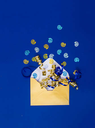 Beautiful yellow pearl envelope with sequins and serpentine on a blue background. Holidays conceptの写真素材