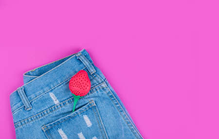 Trendy denim shorts with strawberries in the back pocket against a pink background.の写真素材