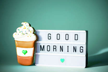 The inscription good morning on a light box with gingerbread on a mint background. Concept