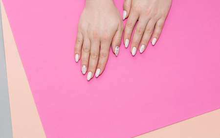 Beautiful stylish female manicure on a gray background with gift in hand. Art contentの写真素材