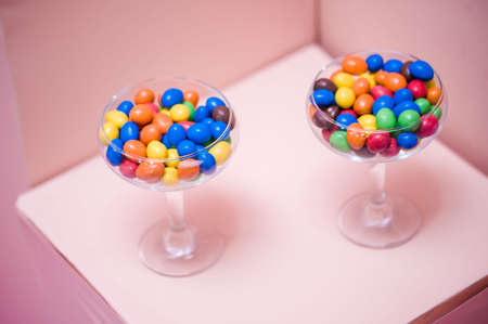 Early-colored round candy in glass glasses. Peanuts in colored chocolate, sweets in a glass.の写真素材