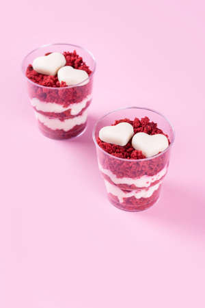 Delicious and beautiful dessert, red velvet in cups. Hearts of white chocolate. Valentine's Day, a place for writing on a pink background.の写真素材