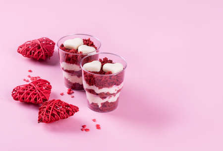Delicious and beautiful dessert, red velvet in cups. Hearts of white chocolate. Valentine's Day, a place for writing on a pink background.の写真素材