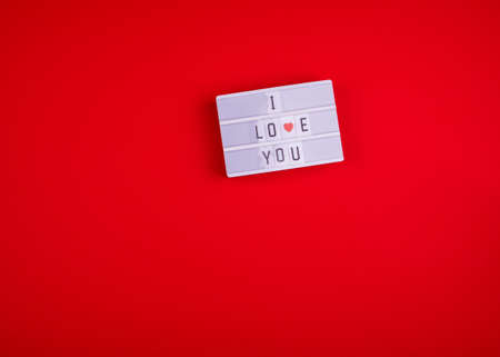 A red background with hearts, a gift, a light box and words i love you. Valentine's Day