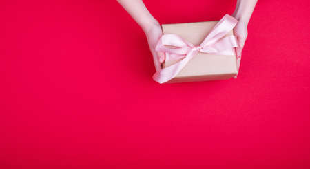 A beautiful gift box with satin ribbon in hand. Banner for content. Place for textの写真素材