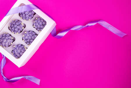 Delicious shawn cupcakes with curd cream in the form of flowers on a pink background. White cupcake...