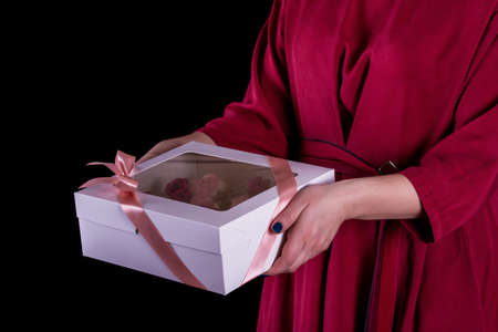 The hands of the confectioner with a delicate and delicious cake of letters. Cake with live flowers, white chocolate, beas. Hands of a pastry chef, packing dessert.の写真素材