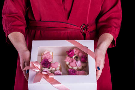 The hands of the confectioner with a delicate and delicious cake of letters. Cake with live flowers,...