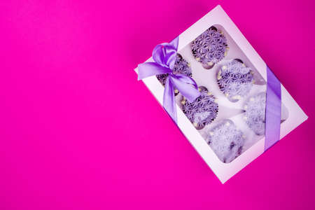 Delicious shawn cupcakes with curd cream in the form of flowers on a pink background. White cupcake...