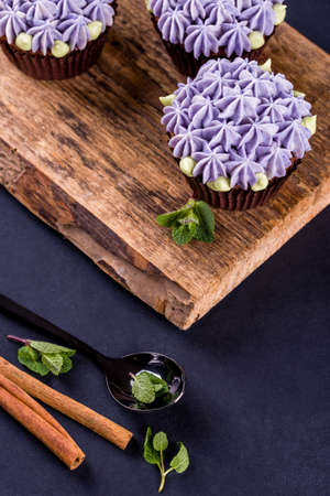 Delicate and beautiful chocolate cupcakes with cream, mint, cinnamon sticks, tea on the table. Tasty foodの写真素材