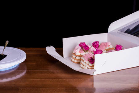 The hands of the confectioner with a delicate and delicious cake of letters. Cake with live flowers,...