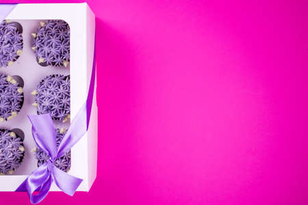 Delicious shawn cupcakes with curd cream in the form of flowers on a pink background. White cupcake...