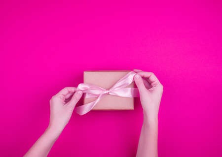 A beautiful gift box with satin ribbon in hand. Banner for content. Place for textの写真素材