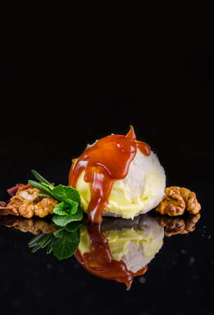 Three colorful balls of delicious ice cream, on a black background with nuts and a sprig of mint. Copy spaceの写真素材