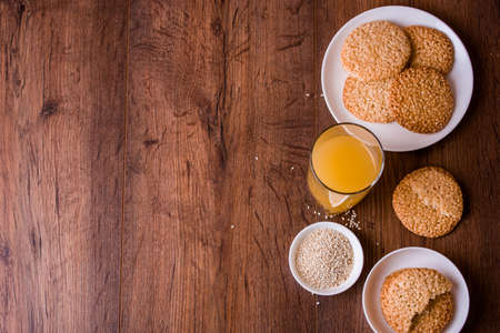 Round sesame cookies with milk and juice on the table. Sesame seeds for bakingの写真素材