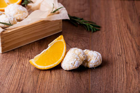 Shortbread orange biscuits with sprigs of semarin, with fresh orange and juice on the table.