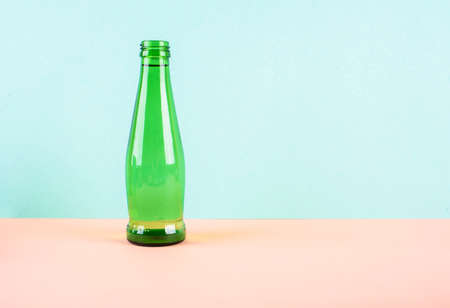 A glass water bottle is bright green on a light background. A place for text.の写真素材