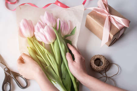 The orange bouquet of tulips is pink. Gift, wrapping paper, ribbons, scissors.の写真素材