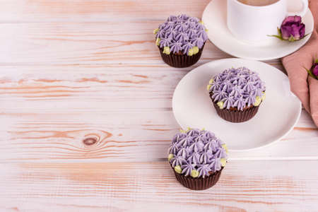 Chocolate delicious cupcake with cream and fragrant coffee with milk on a white wooden table. White dishes for dessertの写真素材