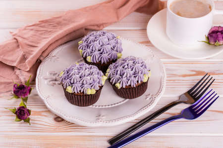 Chocolate delicious cupcake with cream and fragrant coffee with milk on a white wooden table. White...