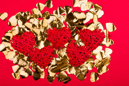 Five red hearts lie on the confetti of gold color. Abstract content, a holiday of lovers. Contentの写真素材