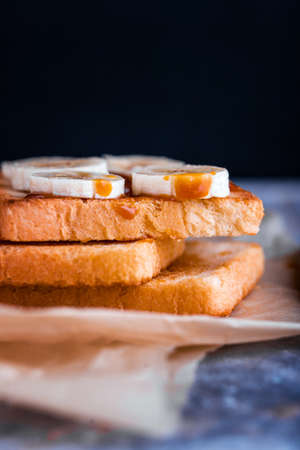 Two delicious toasts with salted caramel and bananas on the table. A healthy breakfast with milk.