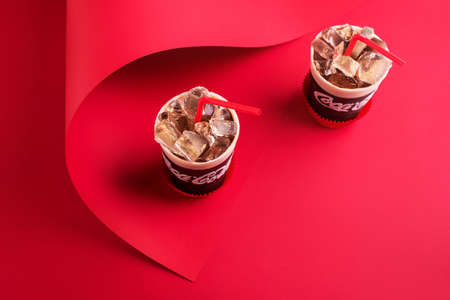 Dessert cake in the form of a glass of drink with ice and a tube on a red background. Caramel, cake, cream, chocolate.の写真素材