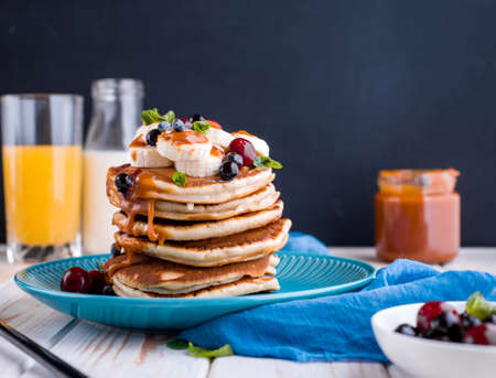 Delicious pancakes with banana, berries, mint and salted caramel in a plate. Delicious breakfast