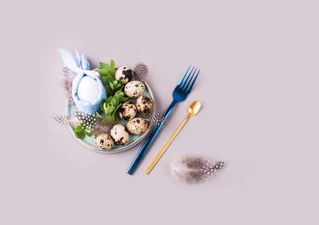 Overquail eggs with young sprigs of green plants on a light background. Holiday content, a place for...