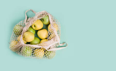 Ripe apples of different varieties in an eco bag on a light background. View from above. Eco...