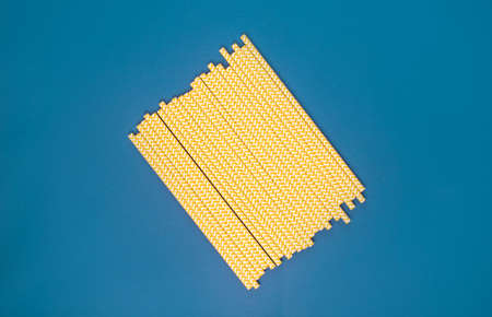 Yellow paper tubes for drinks on a blue background. Abstraction.Eco-friendly alternative concept
