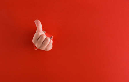 Torn red paper with a hand that shows the class. A place for text.の写真素材
