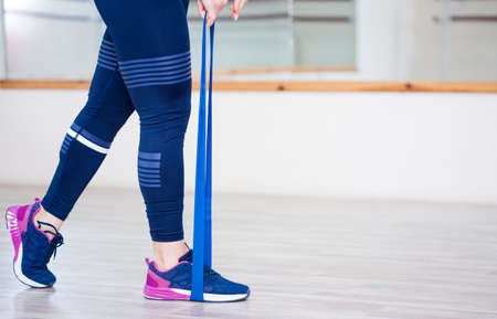 Sports girls play sports with rubber bands in the gym in light tones. Instructor a sport